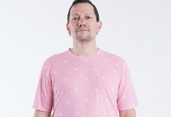 Participant Darryl stands facing the camera wearing a pink shirt.