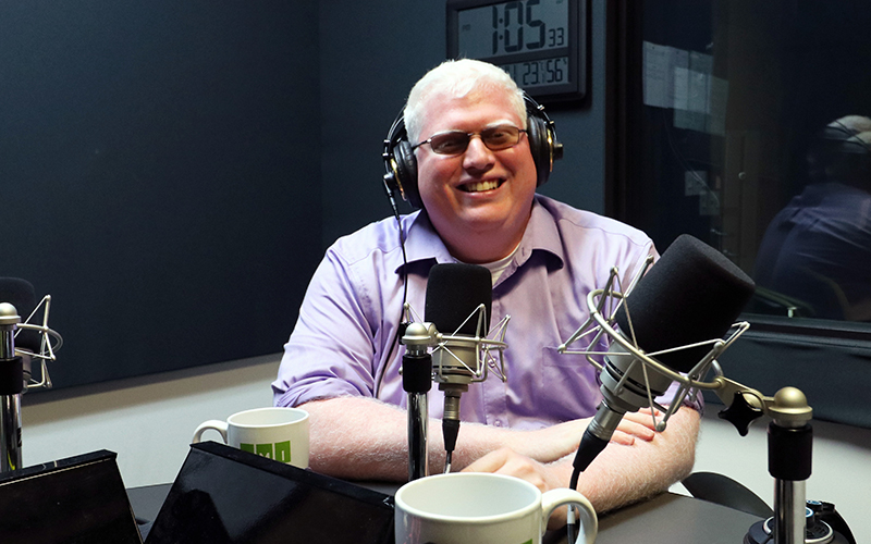 Dave Brown smiles in studio wearing a pair of headphones 