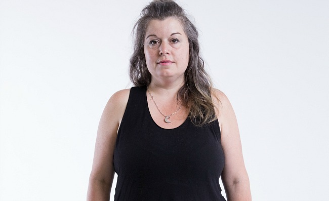 Participant Melanie stands facing the camera wearing a black shirt.