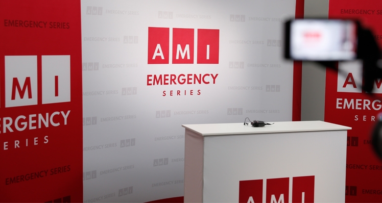 An empty television studio with the AMI Emergency logo displayed.
