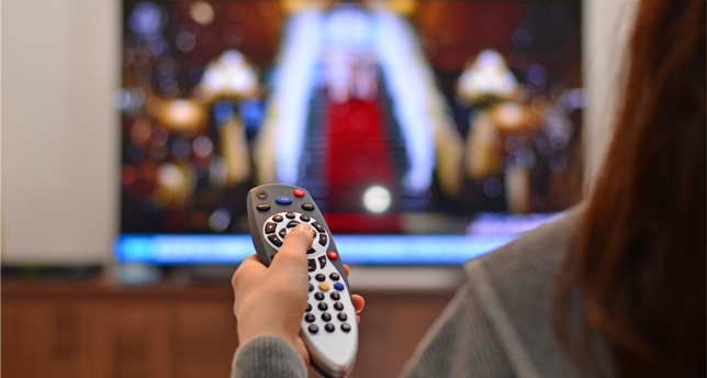 Woman watching TV and using remote controller