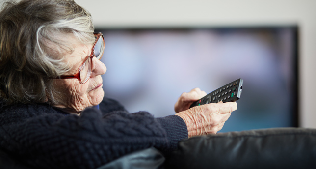 Senior woman holding TV remote control