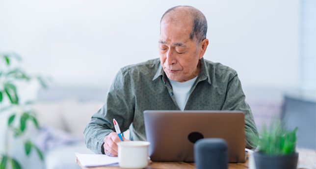 An active senior man is working on a laptop