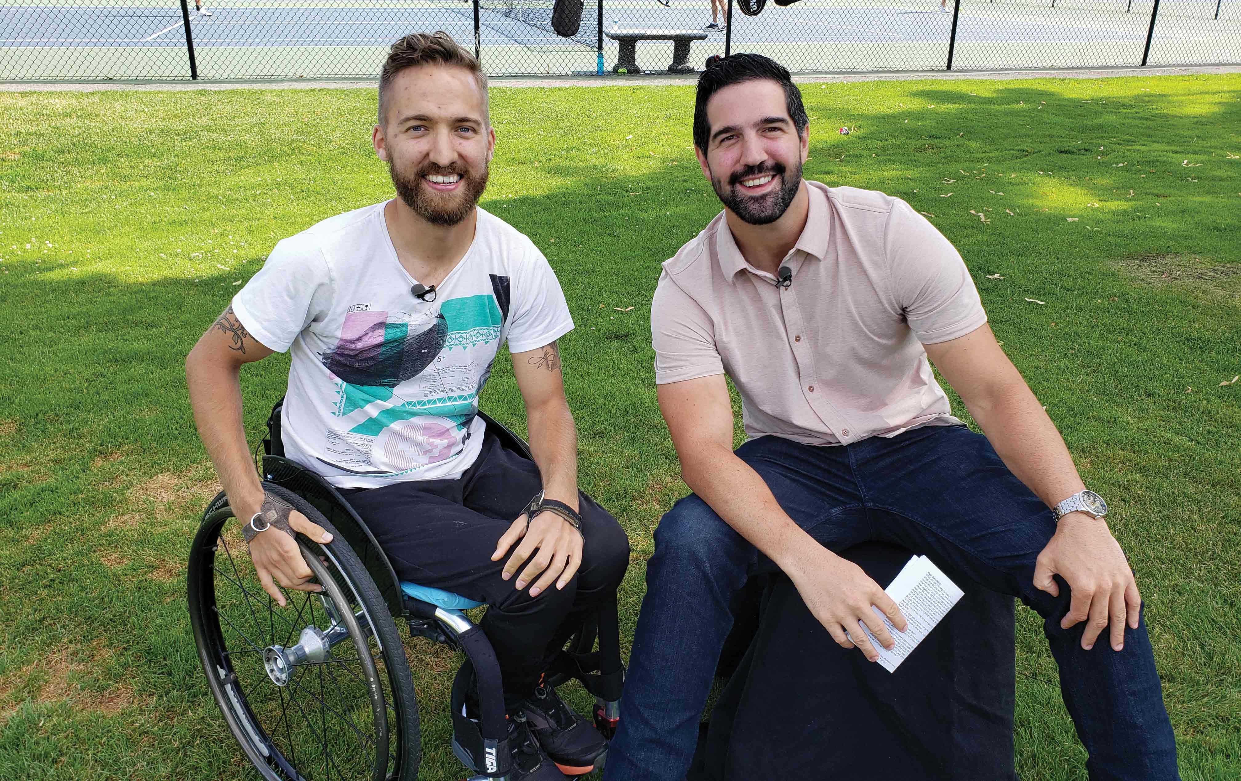 Two men talk on the set of a television show. One is a wheelchair user.