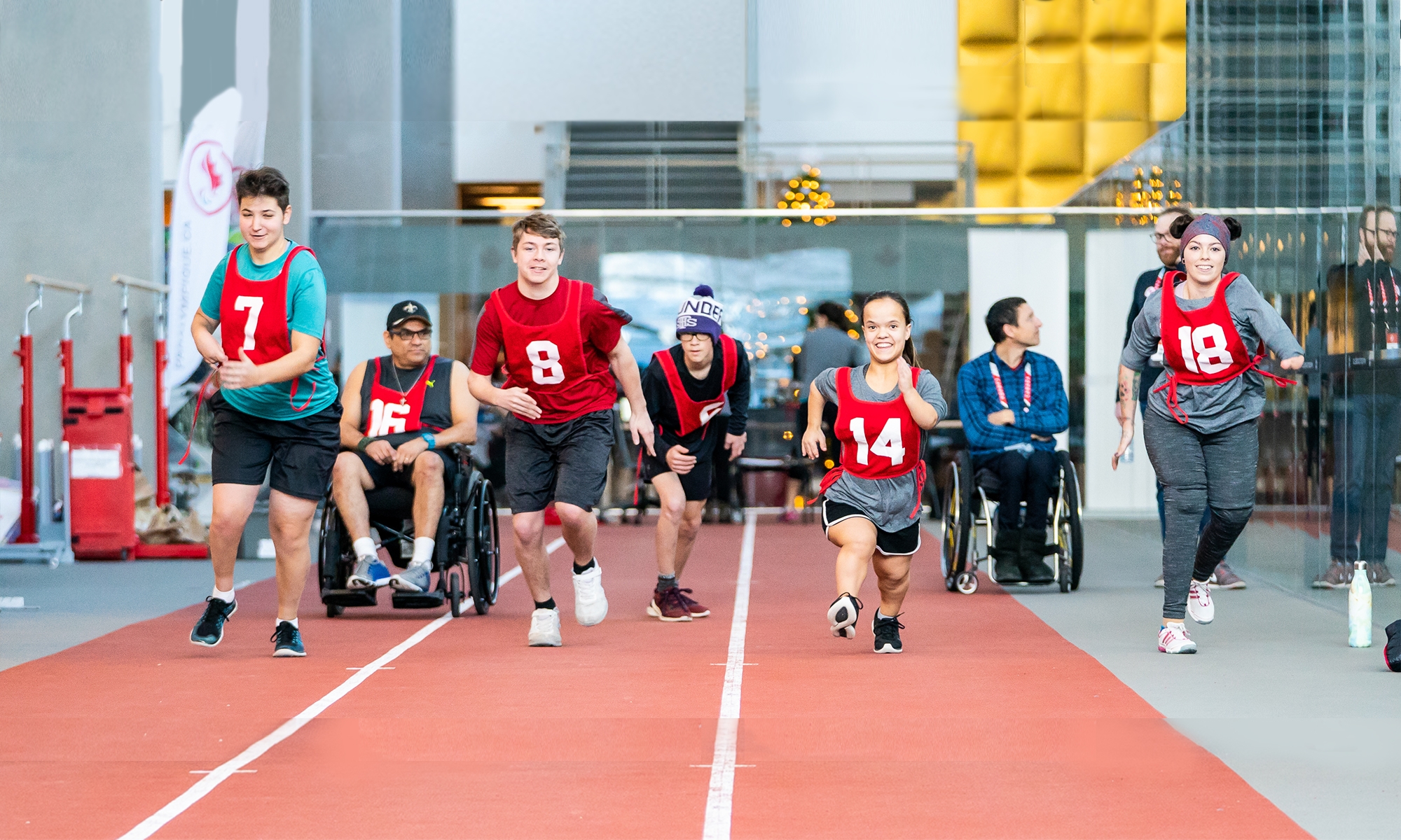 A mixed group of 7 athletes of different body shapes and sizes are shown on a track. Some are in wheelchairs. Photo credit: Canadian Paralympic Committee