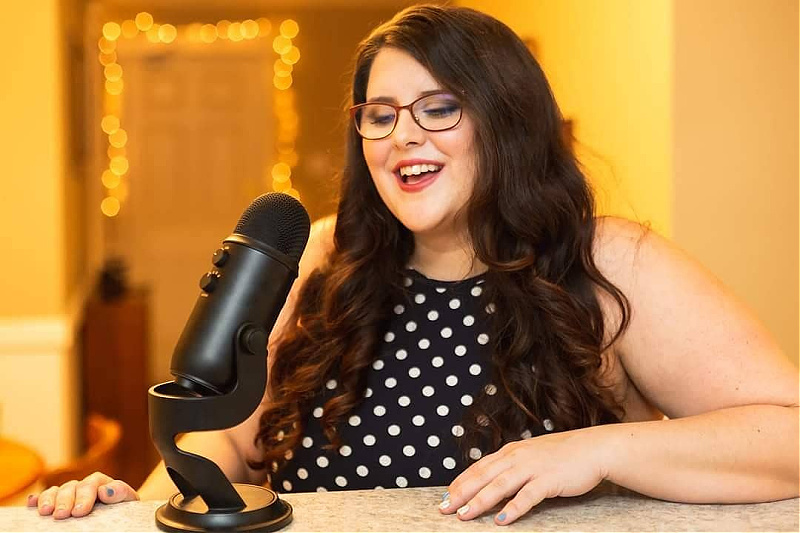 Jillian Gillis sits at a desk, with a microphone in front of her.