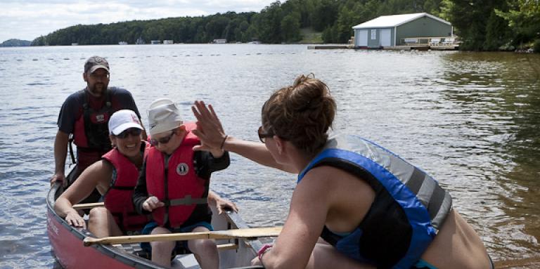 A woman gives a child a high five in a canoe at Lake Joe