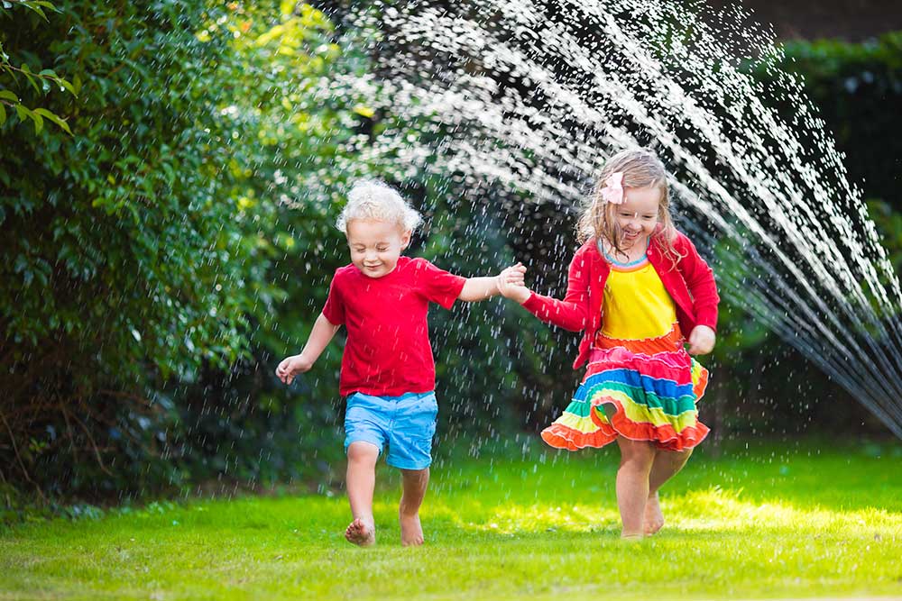 Little kids running threw a sprinkler