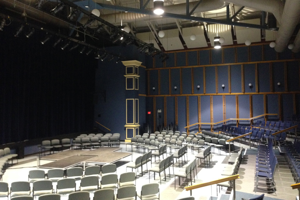 A theatre stage ringed with seats and spotlights overhead