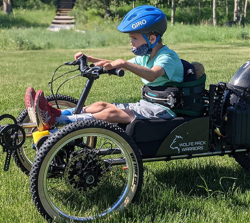 A young boy rides an adaptive bike.