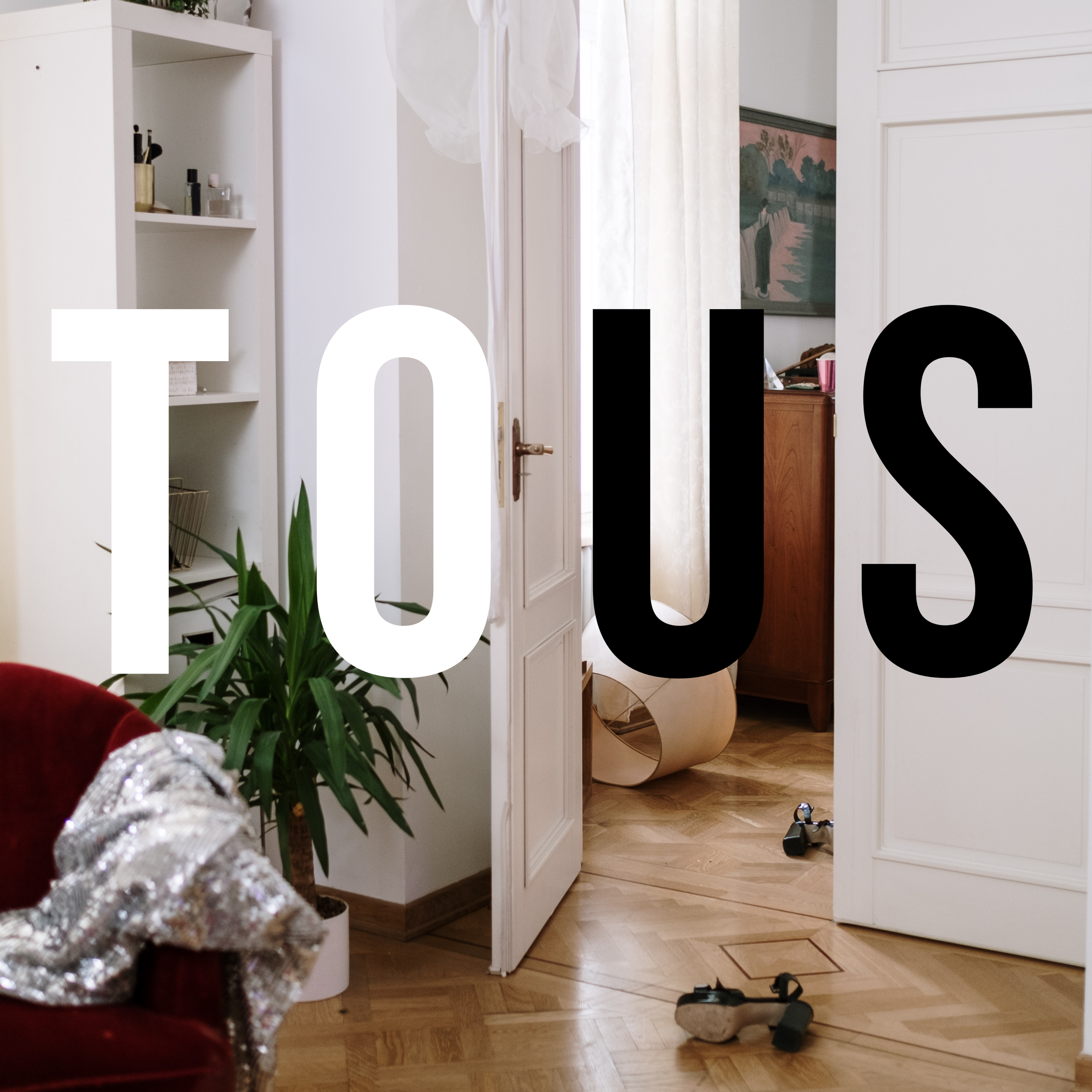 Christa Couture's album cover art of a bedrooms with is door open into the living room. A shirt is tossed on a chair, heels are fallen in the the doorway, a lamp shade is fallen in the background. In large black and white letters are the image reads "To Us."