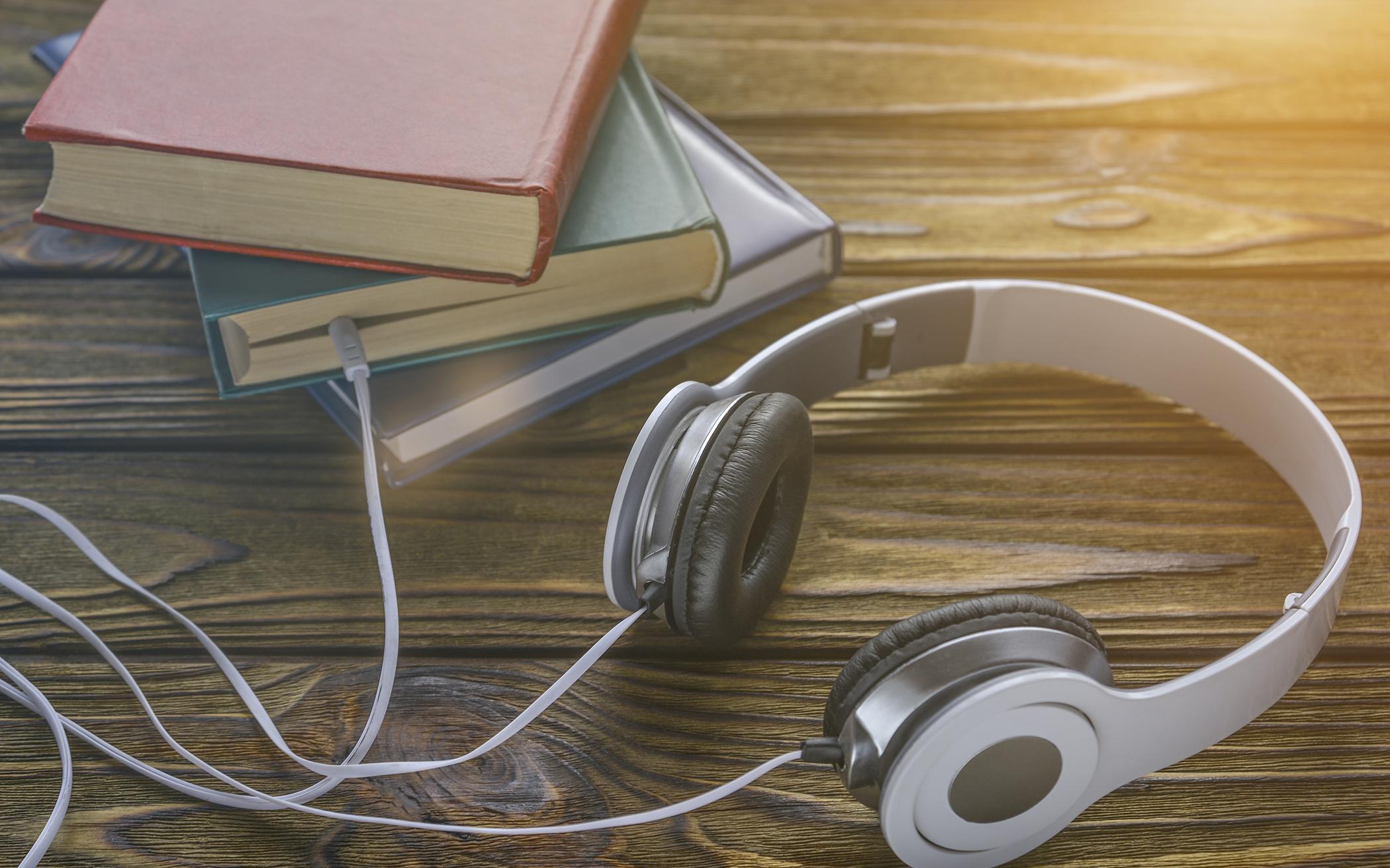 Headphones plugged into a stack of books