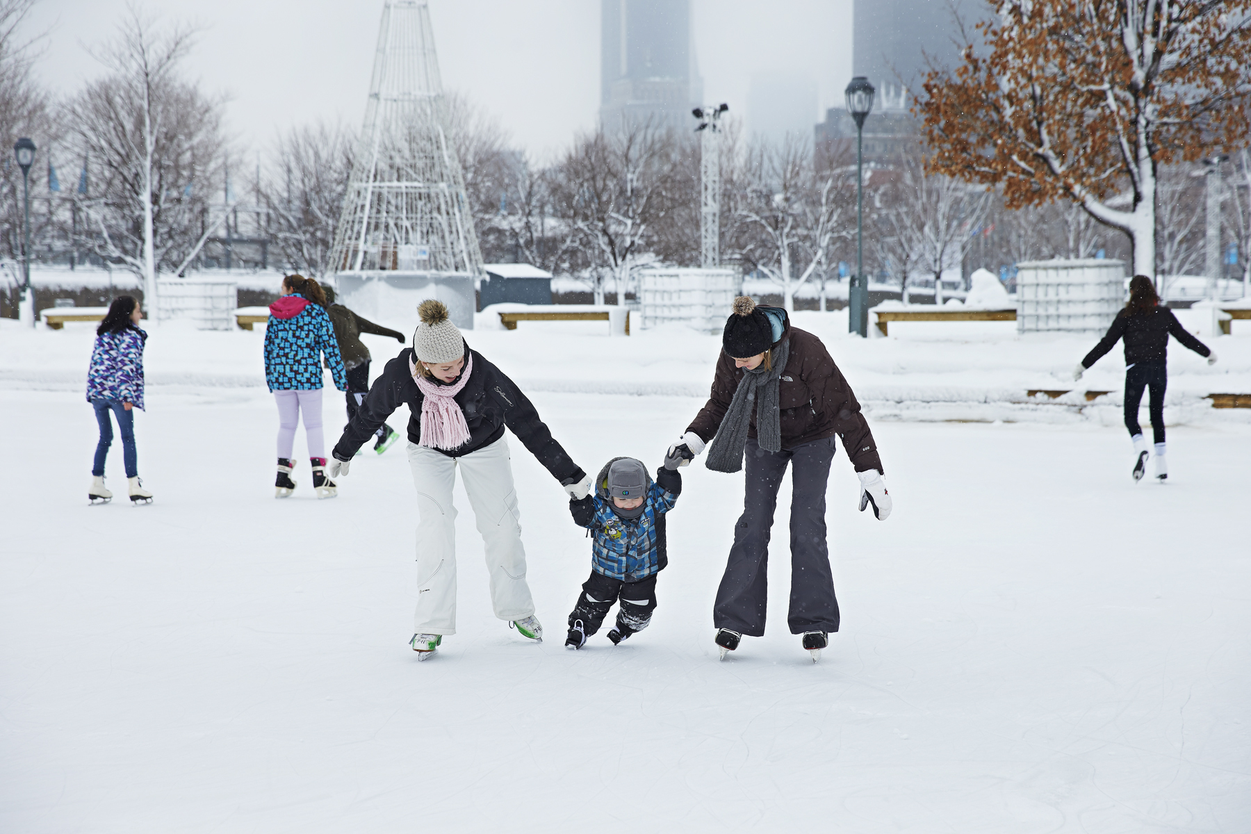 Two adults teaching a child how to skate in the winter