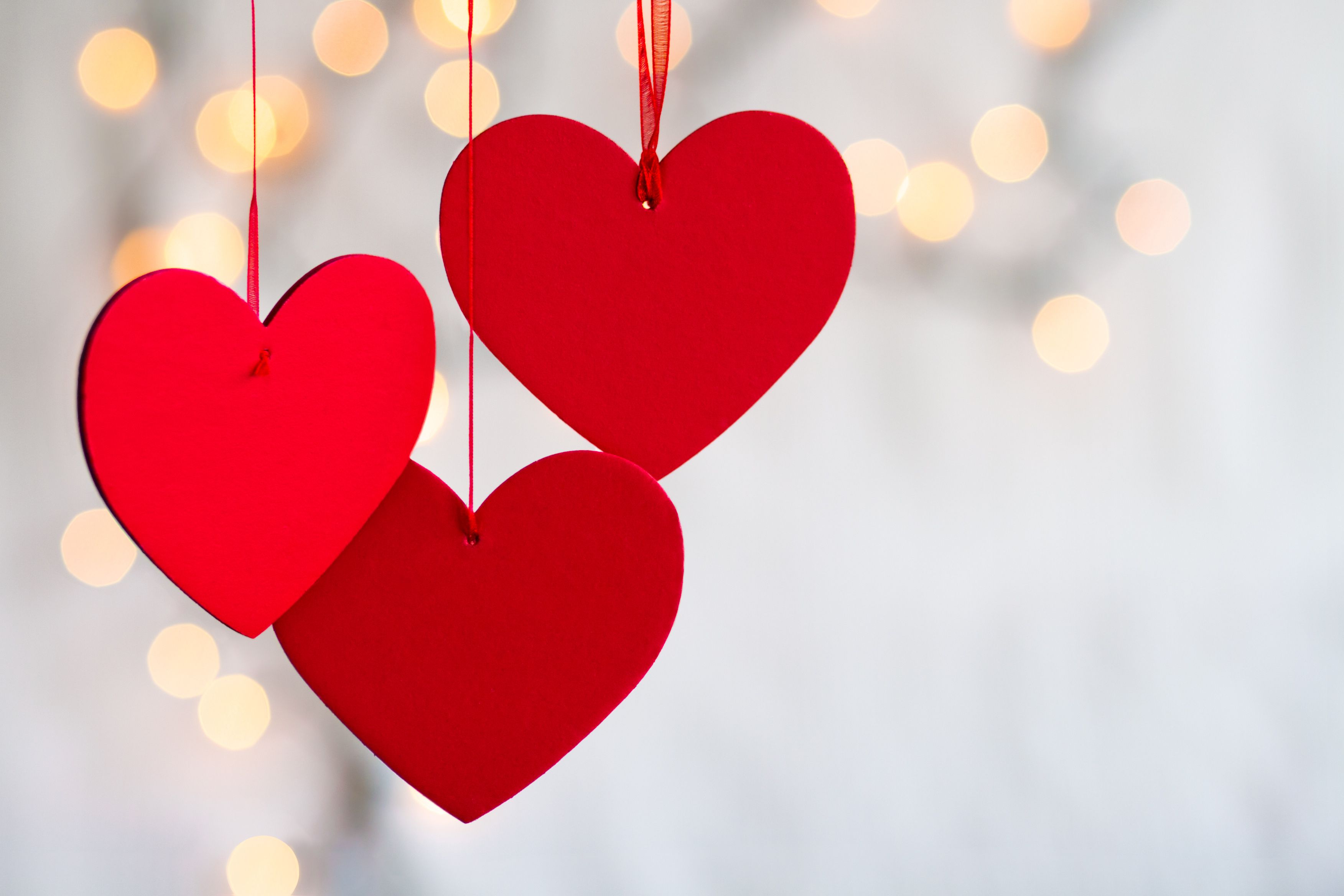 Three hanging red hears on a defocused light background