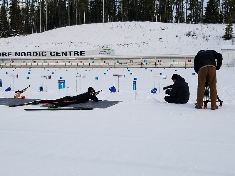 Paralympian Mark Arendz lies flat on the ground, aiming at a target.