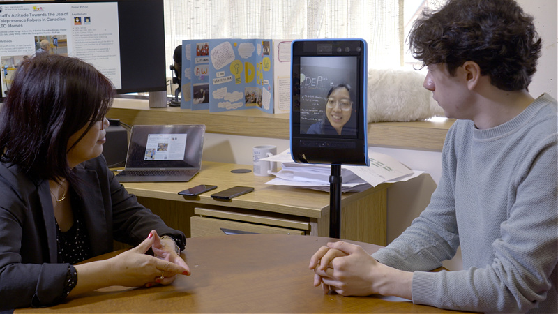 A woman and man look at an iPad mounted on a steel arm.