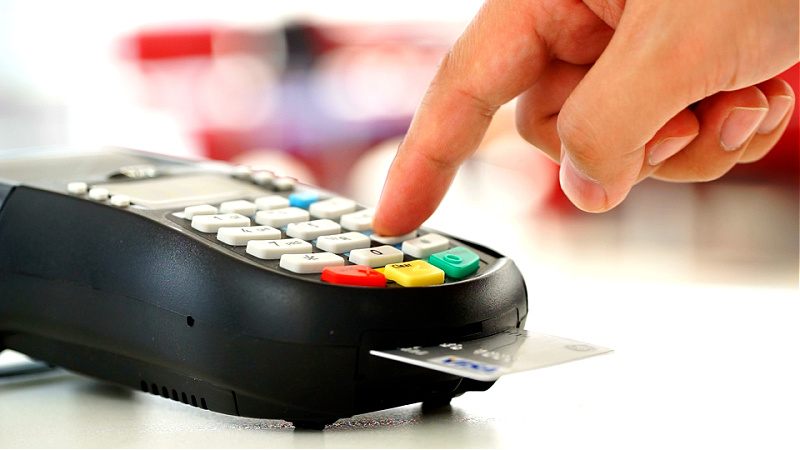 A hand is shown pushing a button on a portable ATM device.