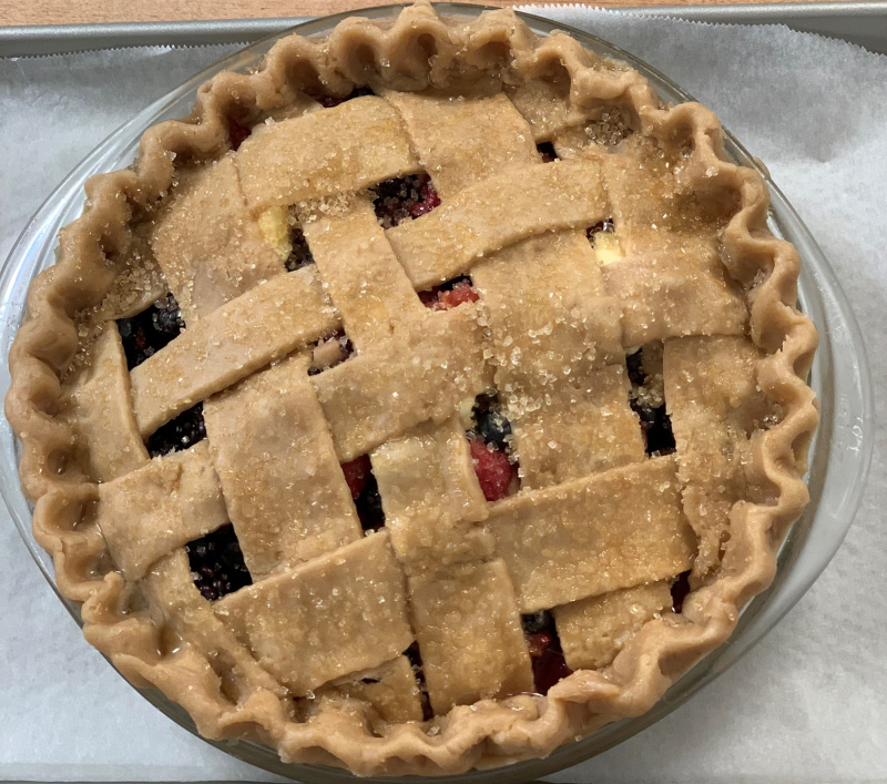 A mixed berry pie, unbaked, sitting on a cookie sheet.