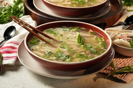 A bowl of pho on a table.