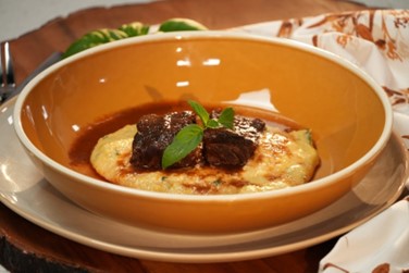 A bowl of polenta with short rib on top.