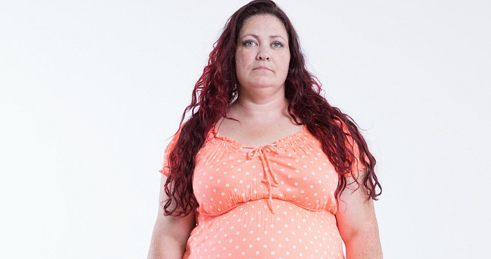 Participant Dana stands facing the camera wearing an orange top.