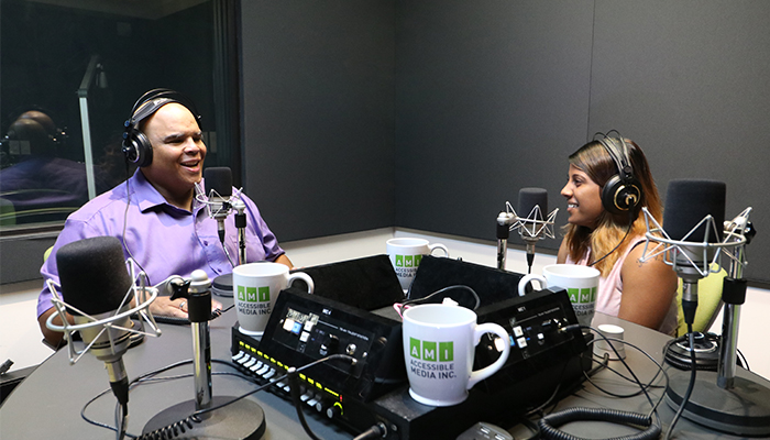 Kelly and Ramya sitting at the studio 5 round table with headphones on