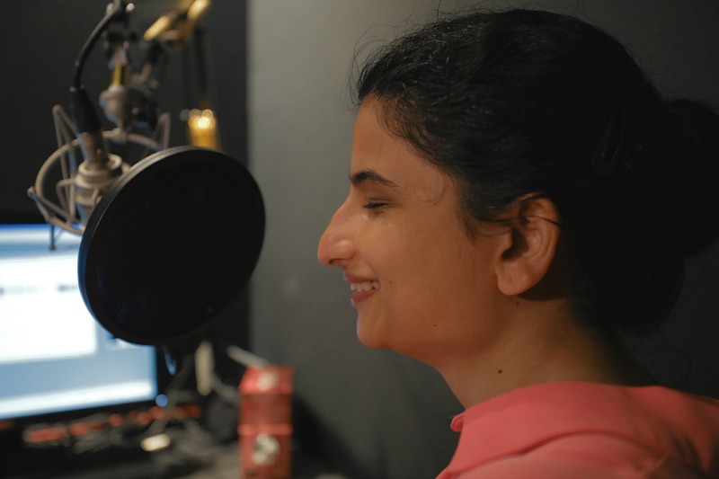 A woman sits at a microphone.
