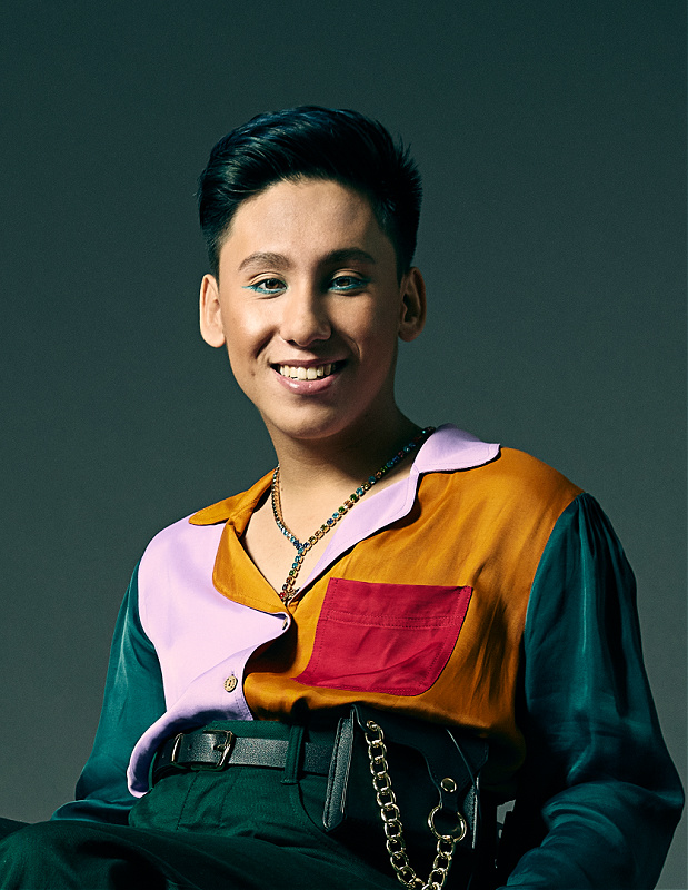 Tai smiles into the camera. He is seated in a wheelchair.