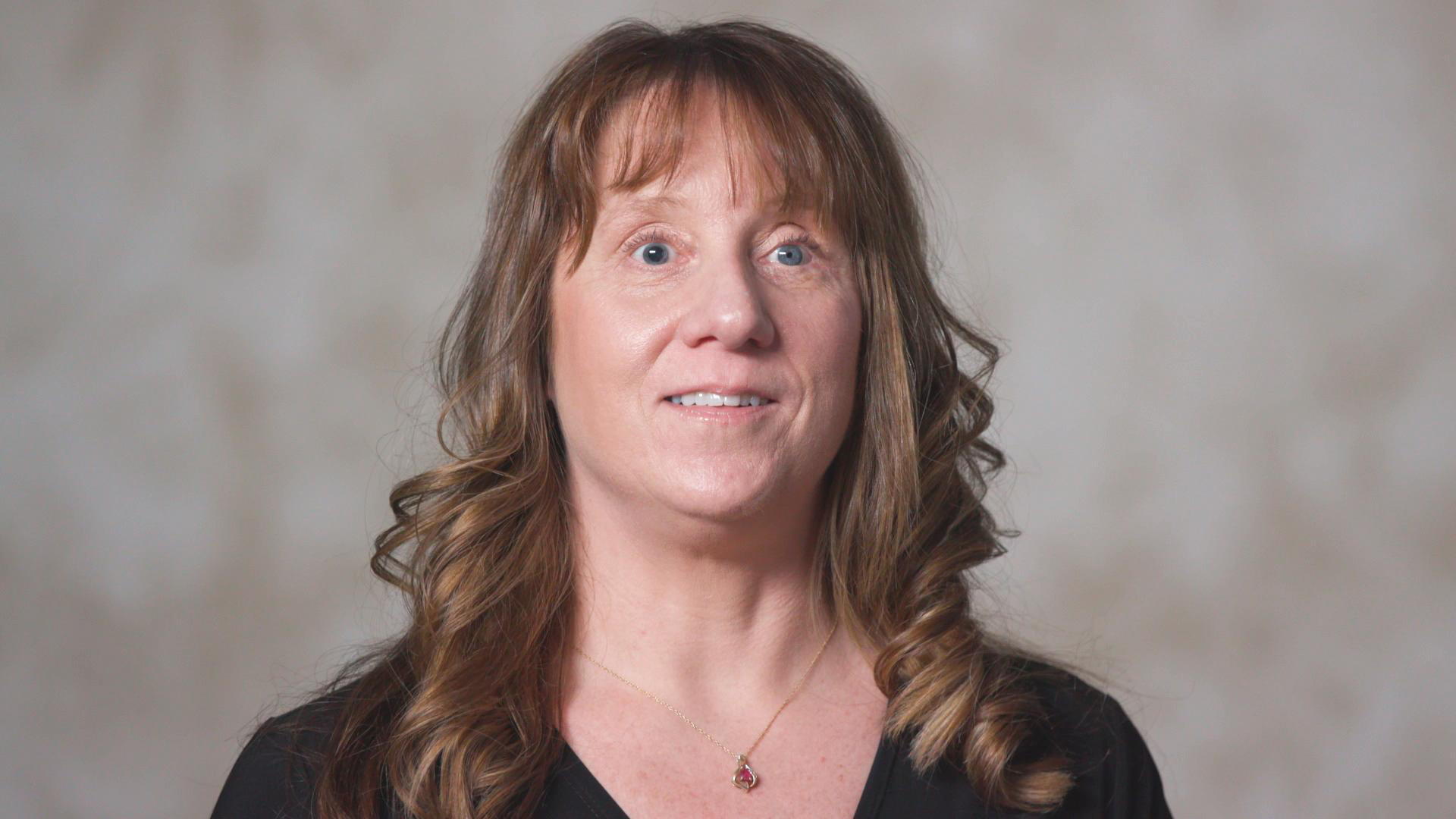 A woman faces the camera, smiling.