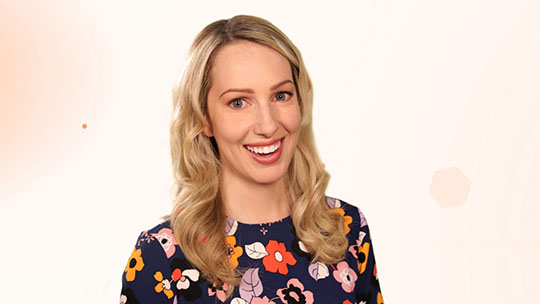 Tasia Custode smiles while wearing a colourful shirt with a flower pattern.