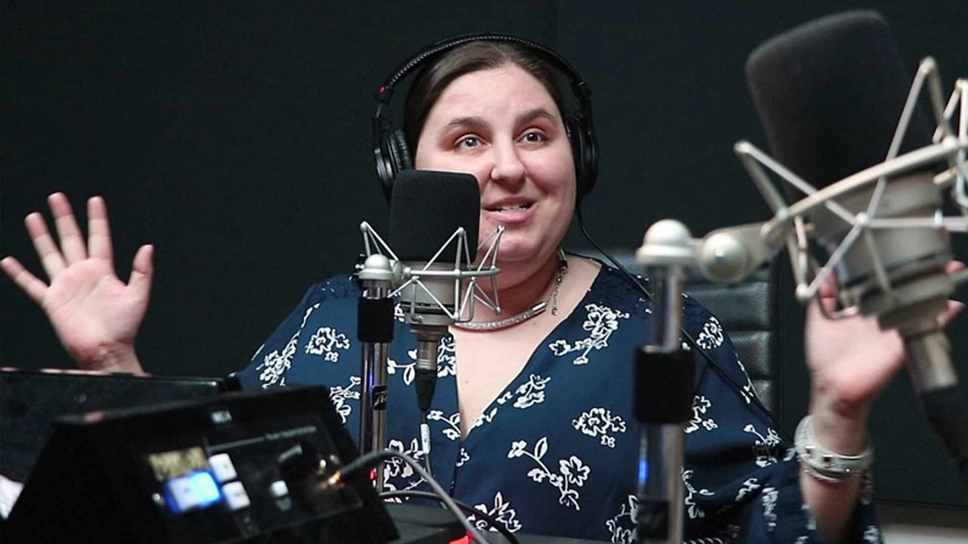 Amy Amantea smiles as she speaks into a radio microphone.