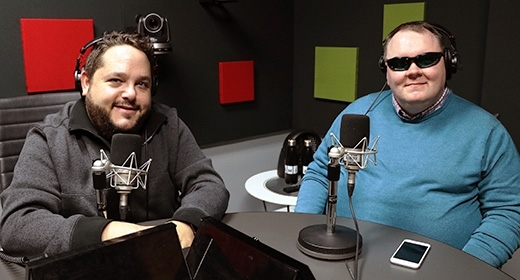 Two men sit in an audio studio.