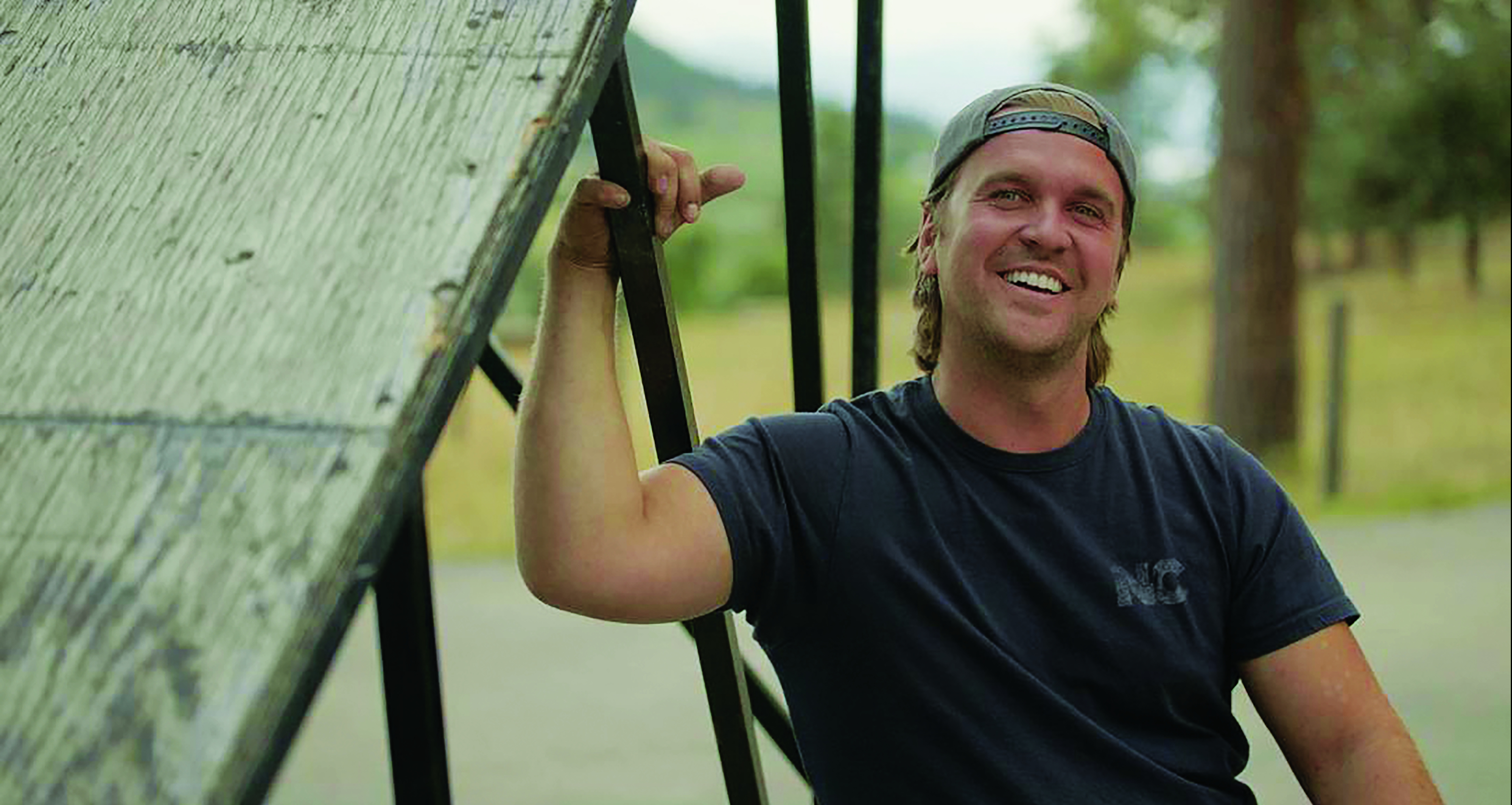 Bruce Cook smiles into the camera. He is seated in a wheelchair.