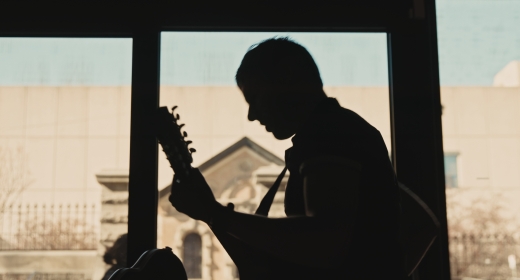 A silhouette of a man playing a guitar.