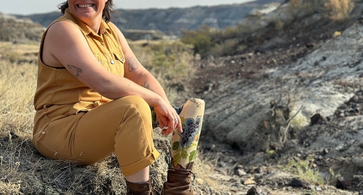 Christa Couture sits on a rock outcropping smiling.